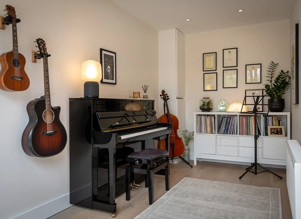 The Music Garden studio, with a piano and string instruments in a bright, welcoming room